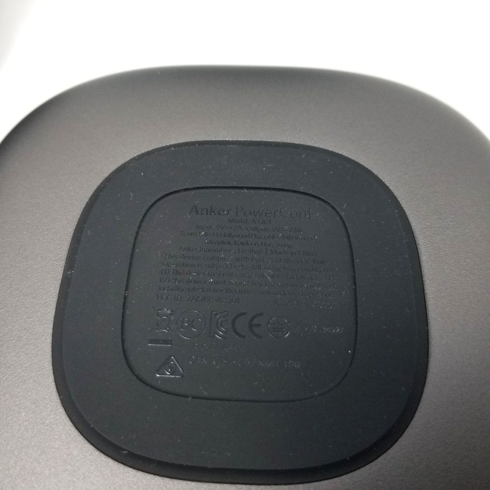 Black wireless charging pad with 'Anker PowerPort' branding on a gray background