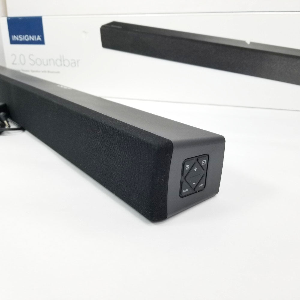 Insignia 2.0 soundbar showing control buttons on the side on a white surface with packaging in the background