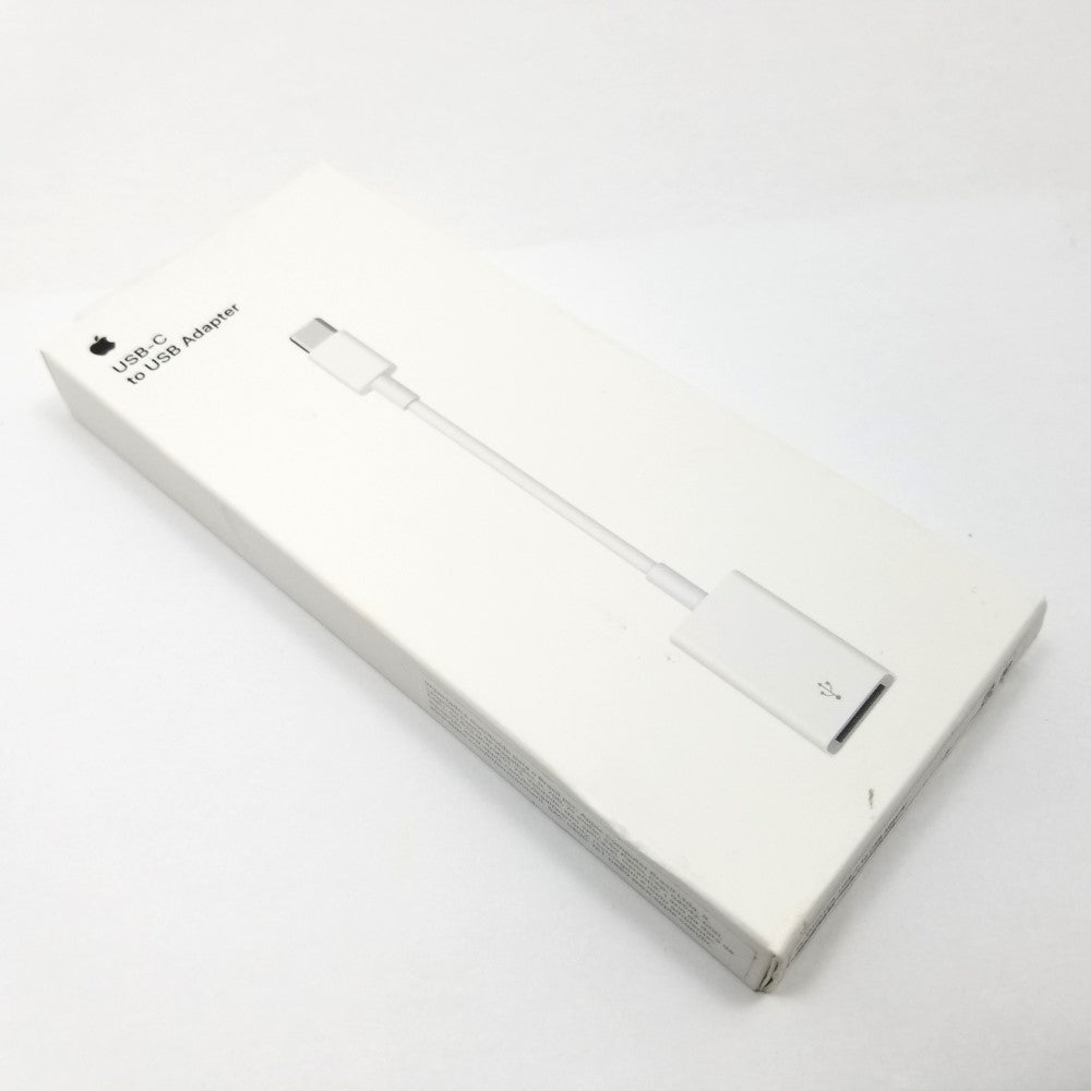 Apple USB-C to USB-A adapter cable in original packaging lying diagonally on a white surface.