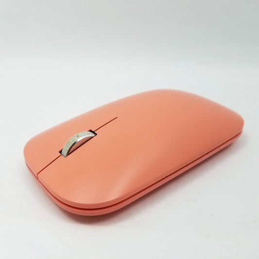 A peach-colored Microsoft Bluetooth wireless mouse with a smooth surface and a visible scroll wheel. Sitting on a white surface