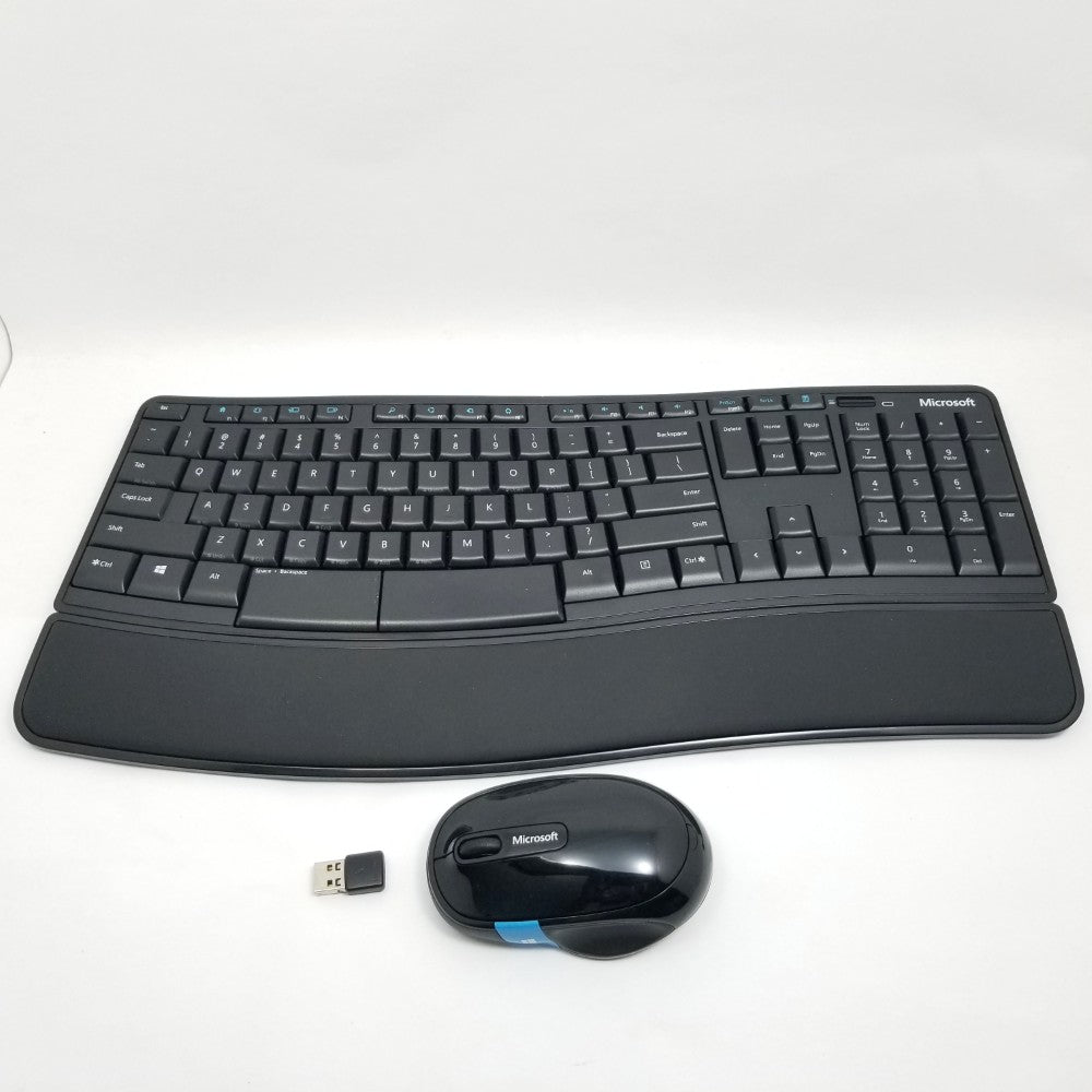 Black ergonomic keyboard and mouse set with Microsoft logo, wireless receiver on a white background
