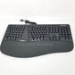 Microsoft ergonomic Keyboard with visible wire and USB plug, sitting on a white surface