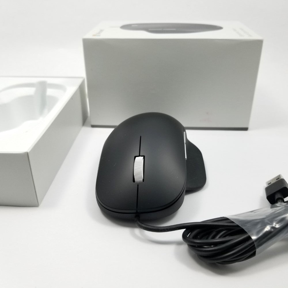 Microsoft wired ergonomic mouse sitting on a white surface with retail packaging sitting in the background,