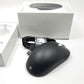 Side profile of Microsoft wired ergonomic mouse sitting on a white surface with retail packaging sitting in the background,