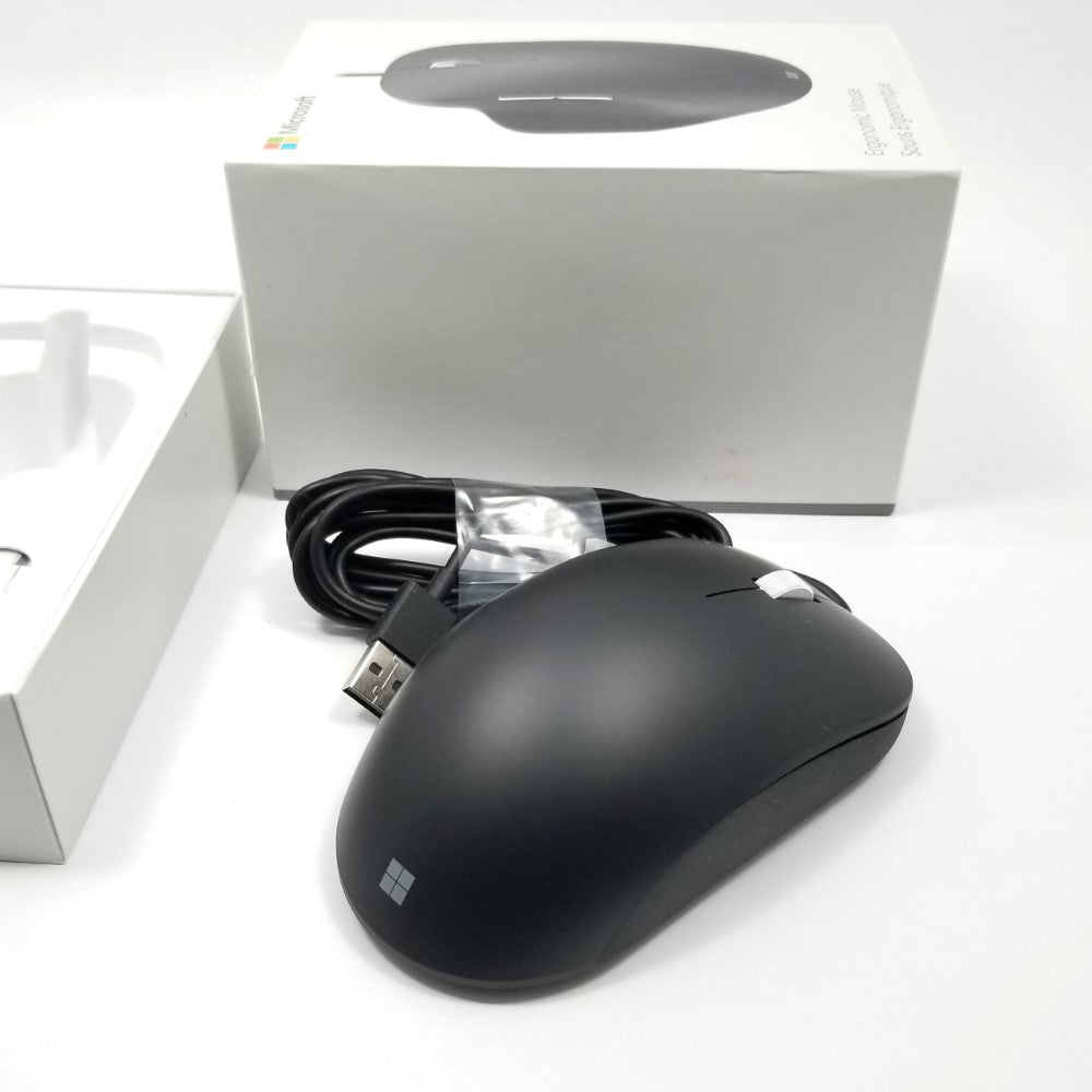 Side profile of Microsoft wired ergonomic mouse sitting on a white surface with retail packaging sitting in the background,