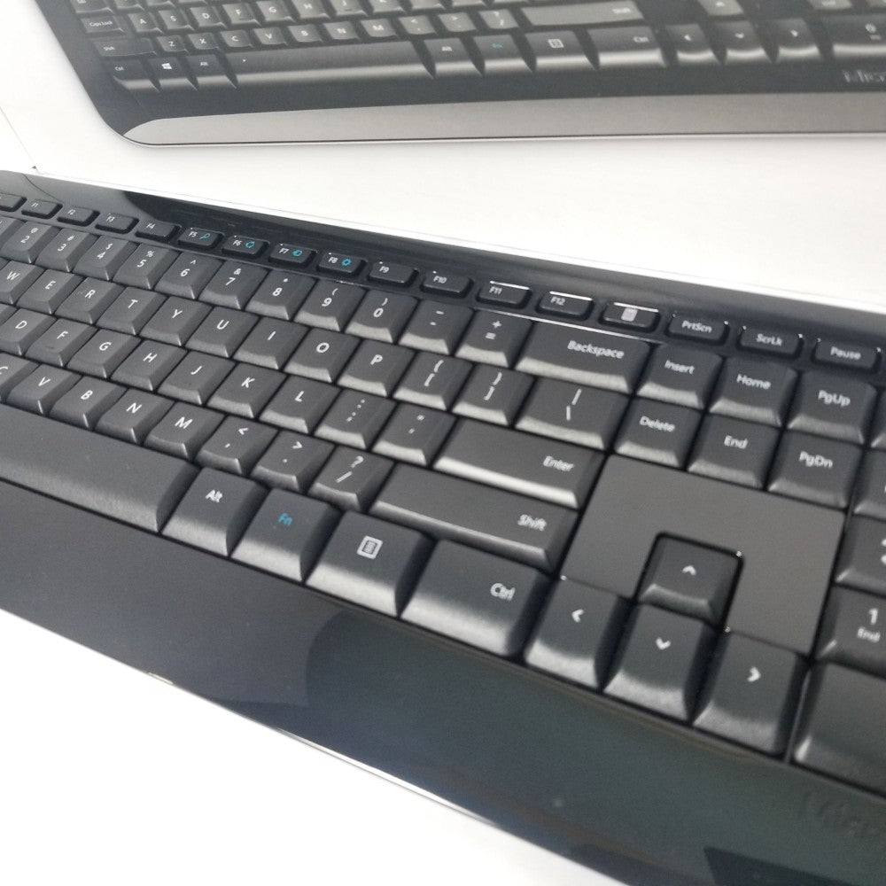 Close-up of keys on a black Microsoft desktop 850 keyboard on a white surface.