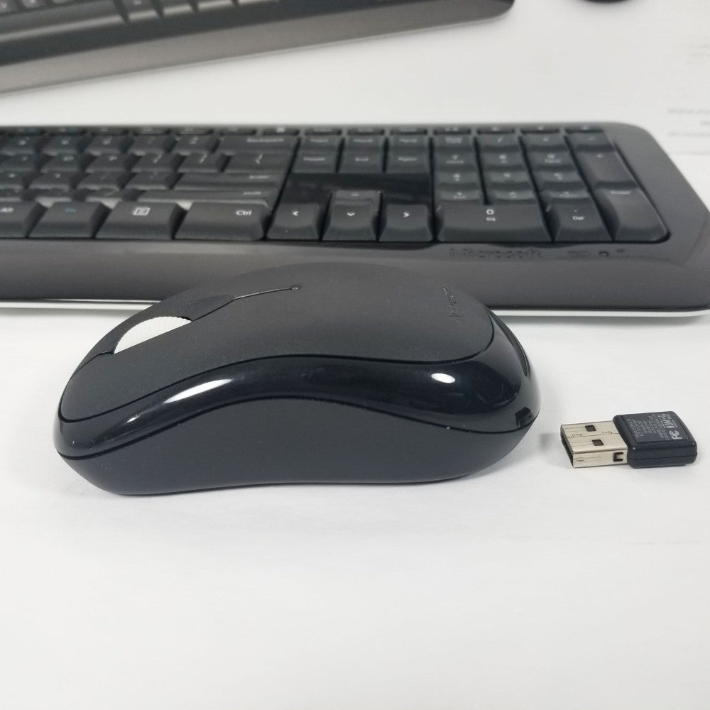 Side profile of Microsoft wireless desktop 850 mouse and wireless receiver with keyboard in the background.