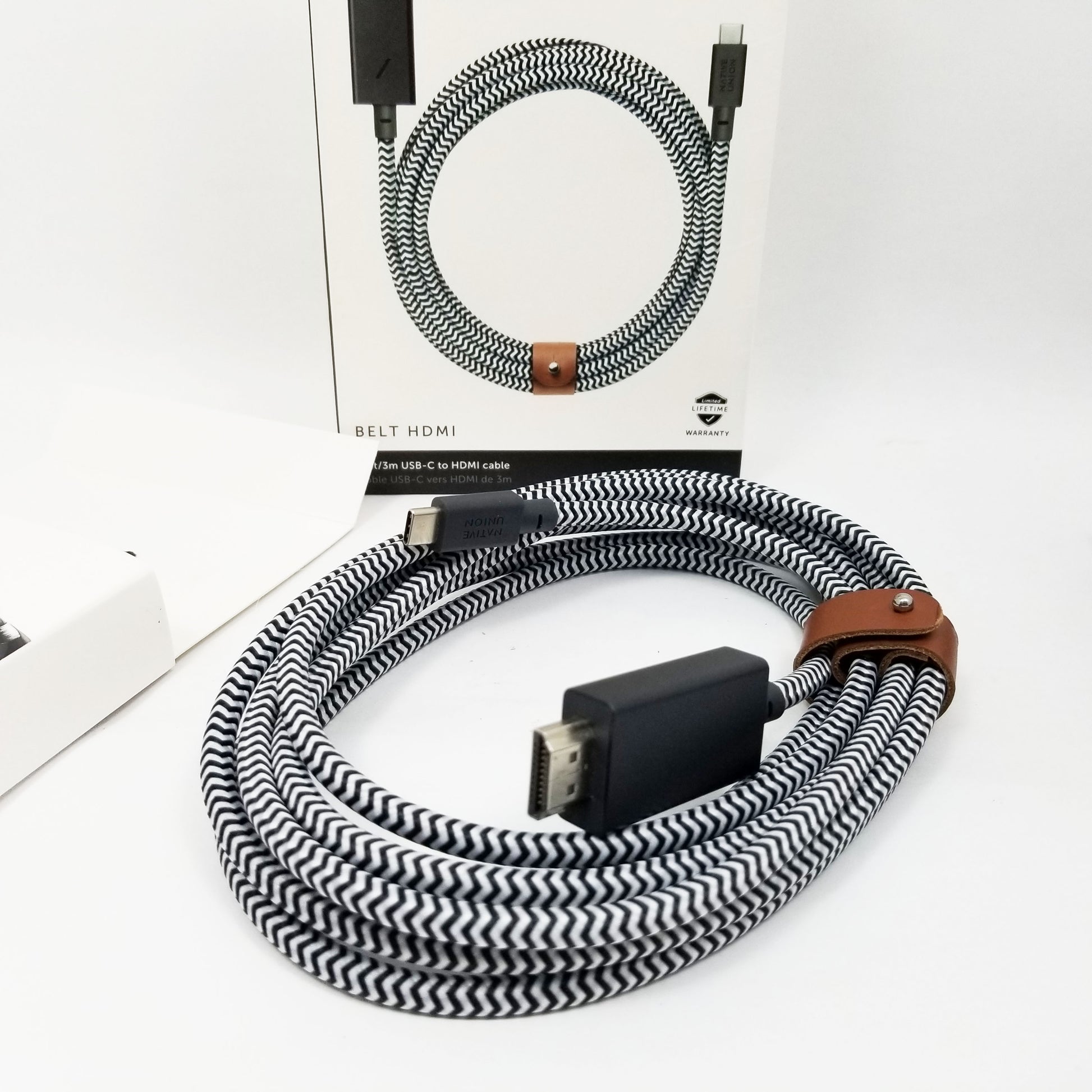Native union USB-c to HDMI cable roller up and tied with brown leather strap on a white background