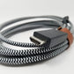 Coiled cable with a braided design showing HDMI port in foreground on a white background
