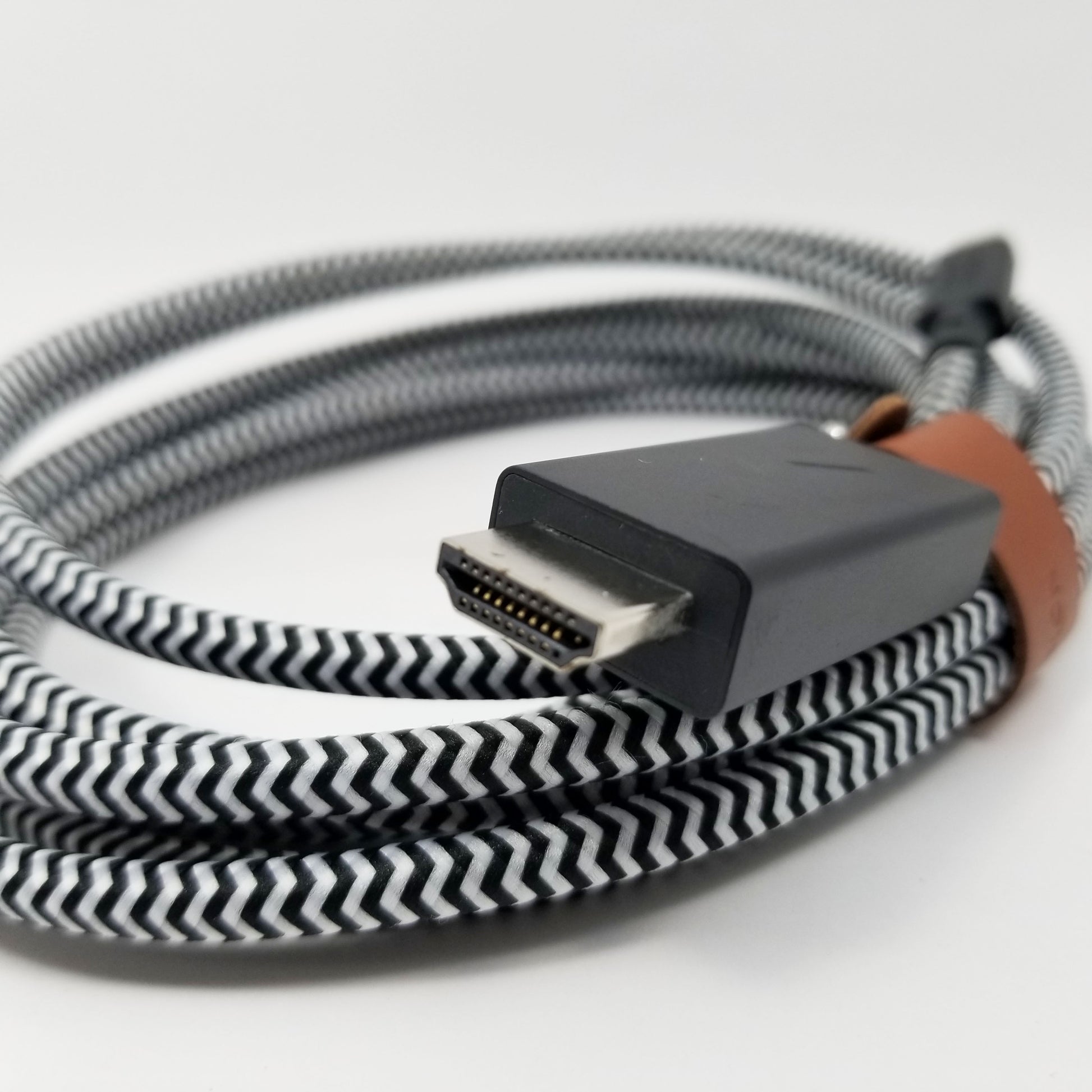 Coiled cable with a braided design showing HDMI port in foreground on a white background