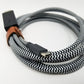 Native union coiled cable with zebra pattern tied with brown leather strap on a white background.