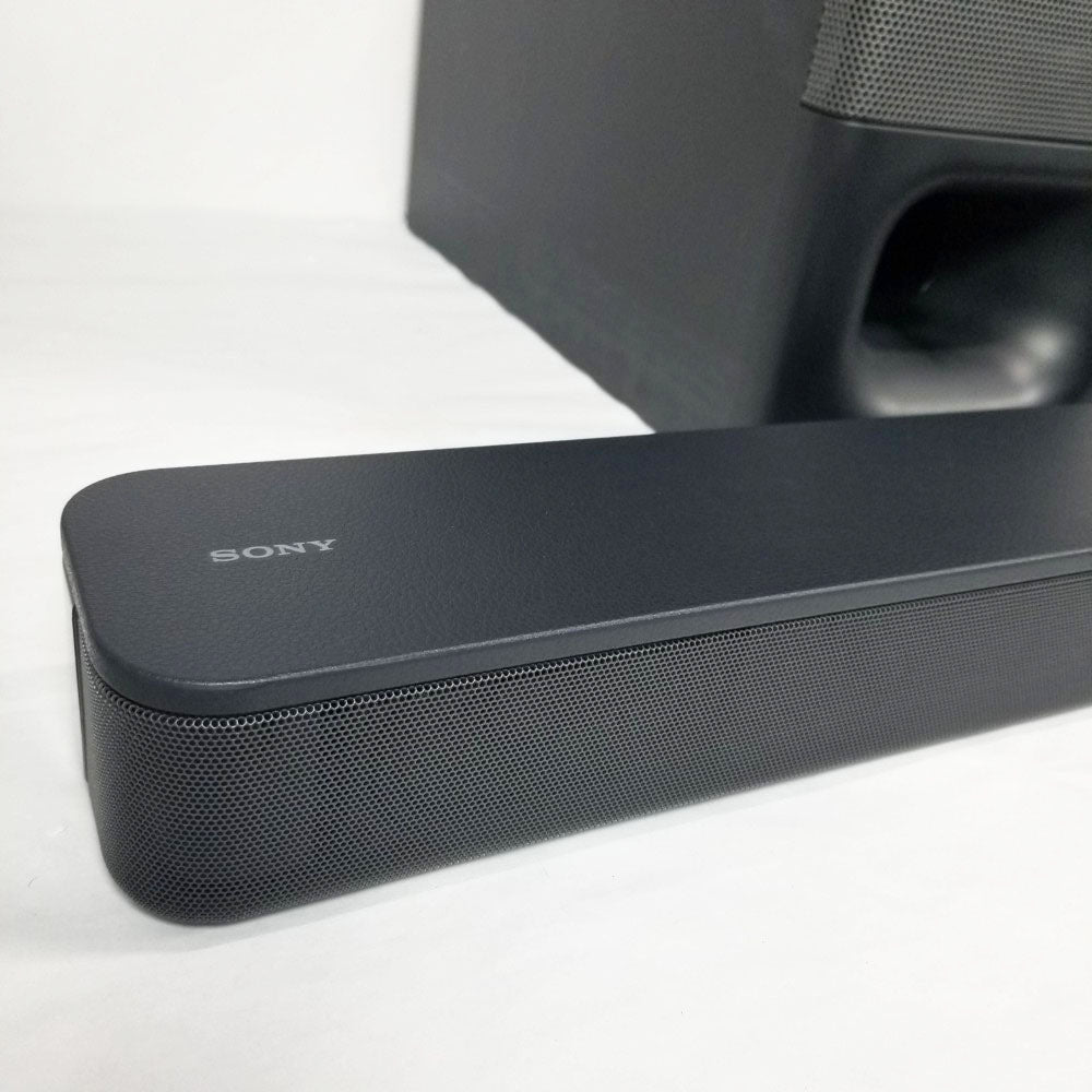 Sony soundbar on a white background. Subwoofer partially visible in the background