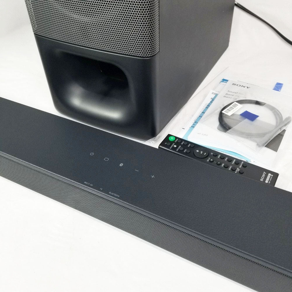 Sony soundbar and subwoofer with remote control and manual on a white surface