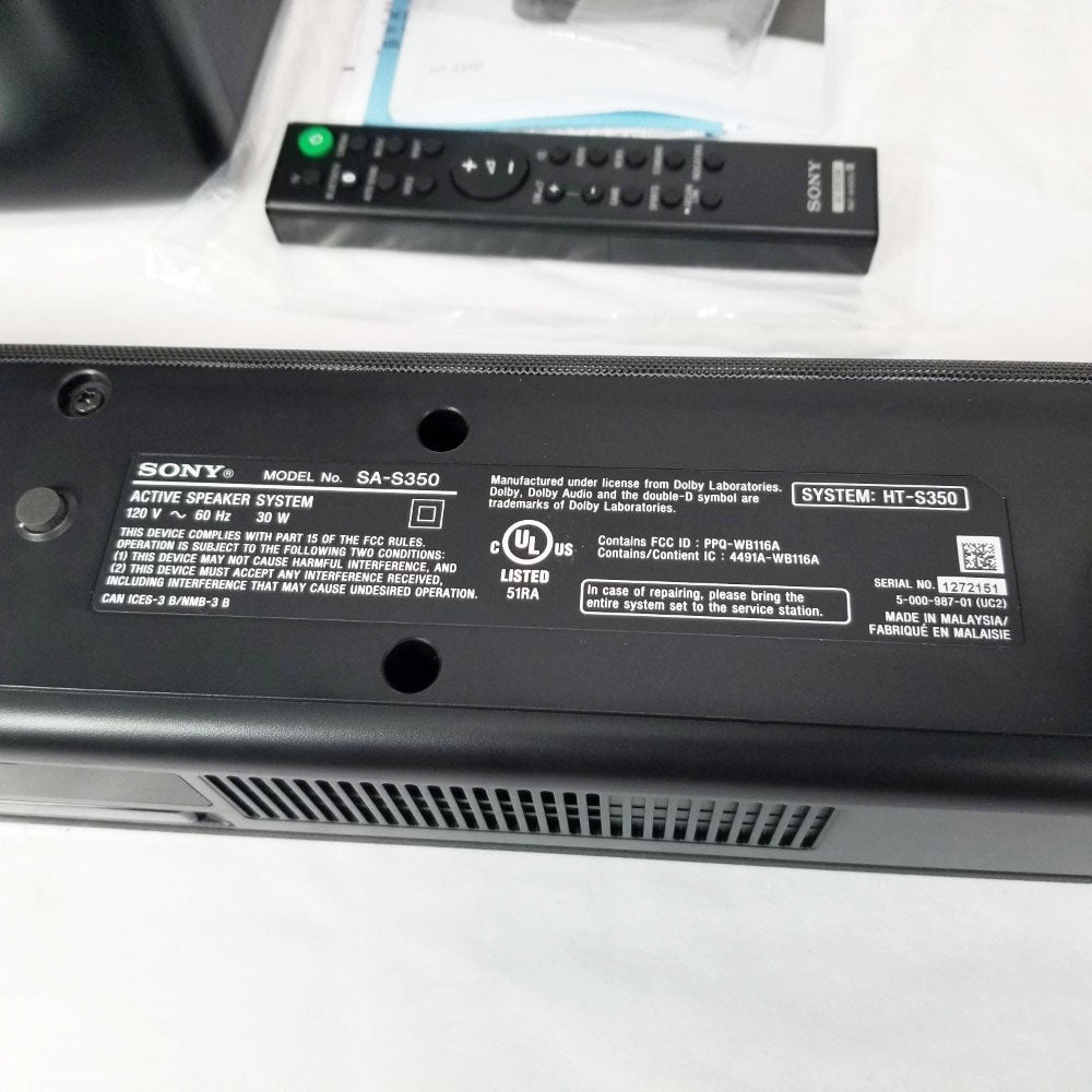 Back of a Sony soundbar showing manufacturer label tag. Remote control sitting to the al on a white surface