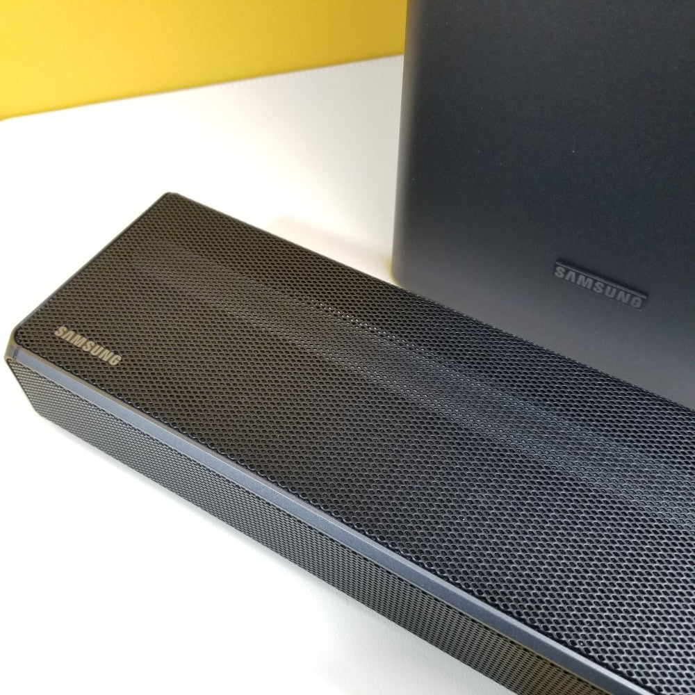 Samsung HW-Q60T soundbar on a white surface with a yellow wall in the background