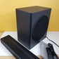 Samsung HW-Q60T subwoofer and soundbar on a white surface with a yellow wall background